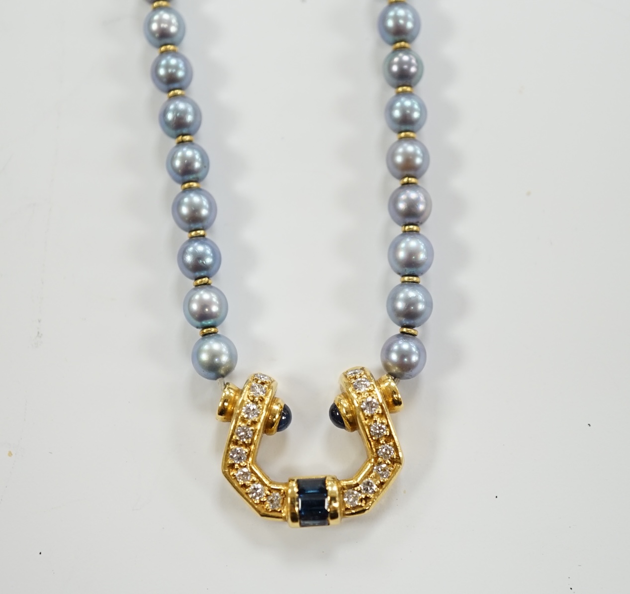 A modern single strand blue cultured pearl necklace, with 750 yellow metal, sapphire and diamond set pendant and yellow metal clasp, 42cm.